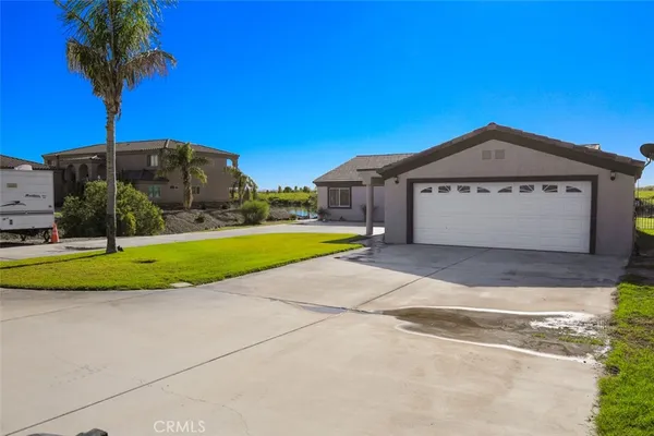 a front view of a house with a yard and palm trees