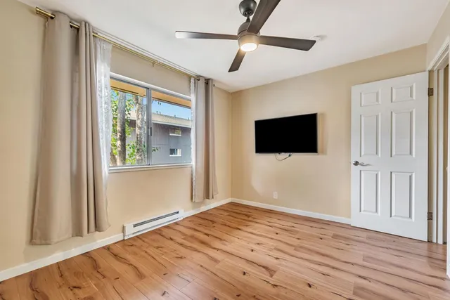 a view of empty room with wooden floor and fan