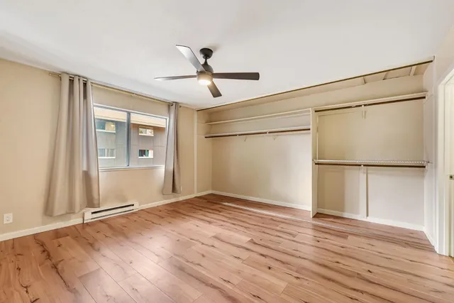 a view of empty room with wooden floor and ceiling fan
