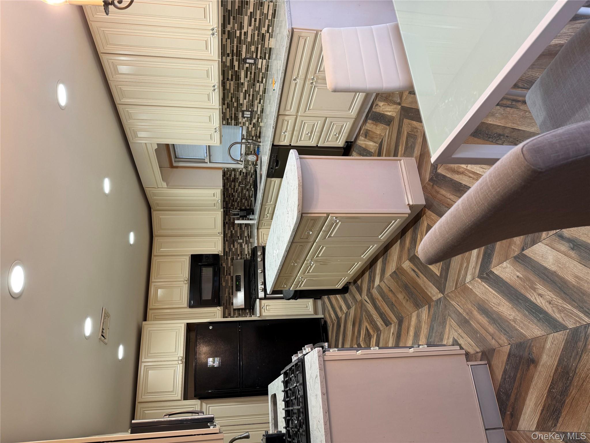 Kitchen featuring light stone counters, cream cabinets, a kitchen island, refrigerator, and dishwashing machine