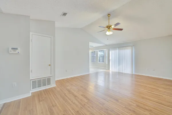 a view of an empty room with a window and wooden floor