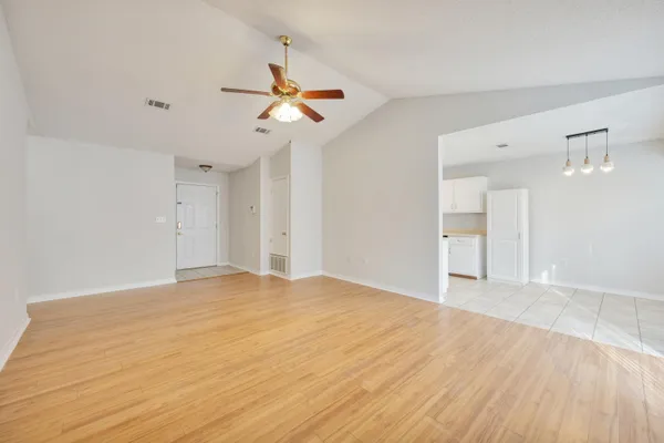 a view of empty room with wooden floor and ceiling fan