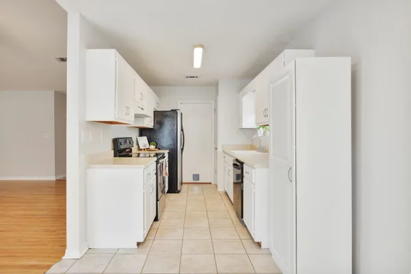 a kitchen with a refrigerator a stove top oven and cabinets