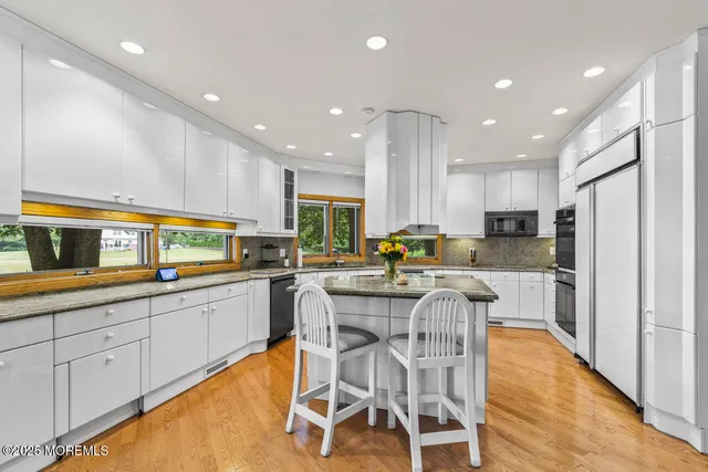a kitchen with granite countertop a refrigerator a sink and white cabinets