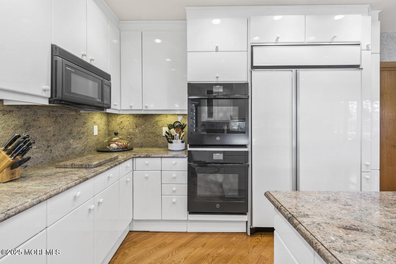 31 Thompson Grove Road Freehold, NJ 07728 - Photo 20 of 54 a kitchen with granite countertop a refrigerator a sink and white cabinets