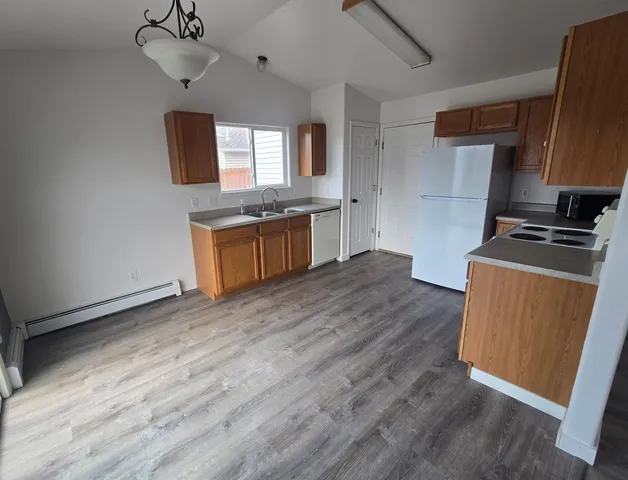 a kitchen with granite countertop a sink cabinets and wooden floor