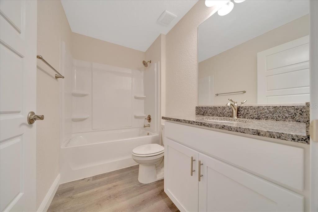 10675 Southwest 69th Terrace Ocala, FL 34476 - Photo 30 of 48 a bathroom with a granite countertop sink toilet mirror and bathtub