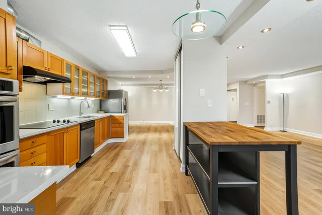 a view of an empty room with wooden floor and a bathroom
