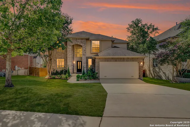 a front view of a house with a yard and trees