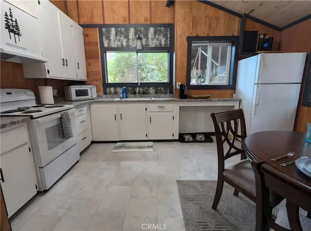 a kitchen with a stove a sink cabinets and a window