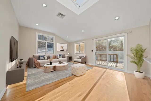 a living room with furniture large window and wooden floor