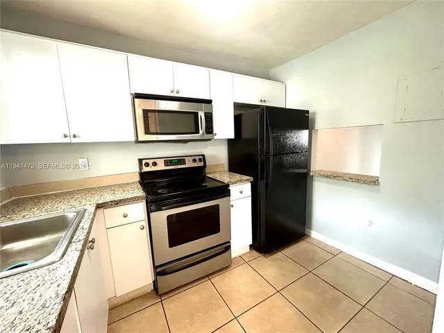 a kitchen with granite countertop a refrigerator and a stove top oven