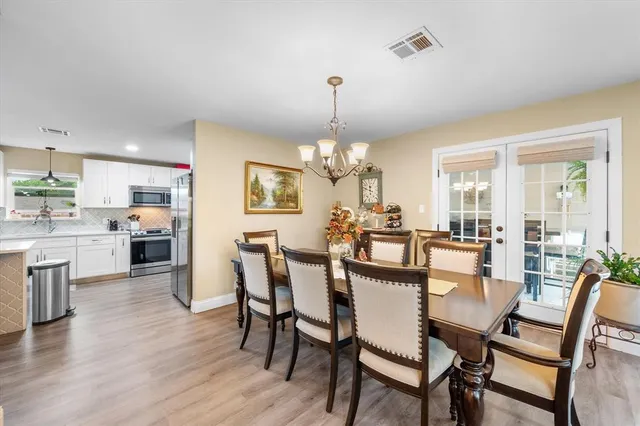 a dining room with furniture a chandelier and wooden floor