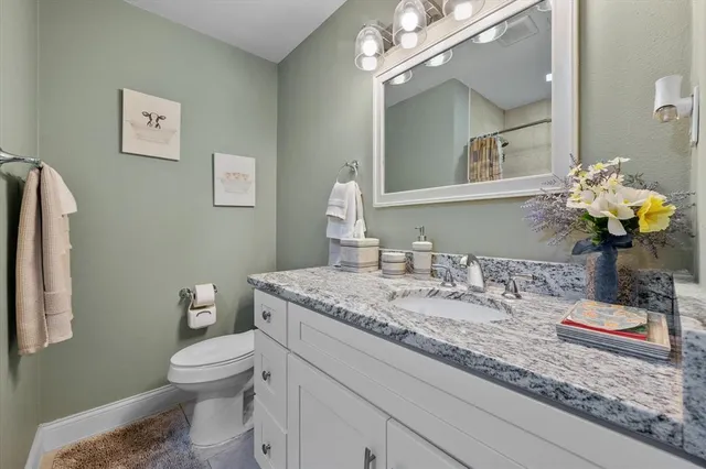 a bathroom with a granite countertop sink a toilet and a mirror