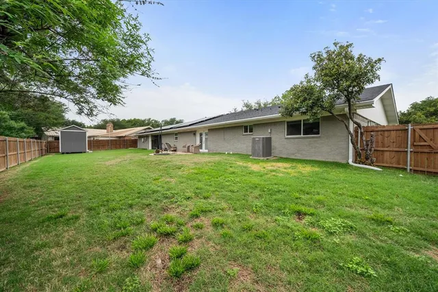 a view of backyard with wooden fence and a large tree