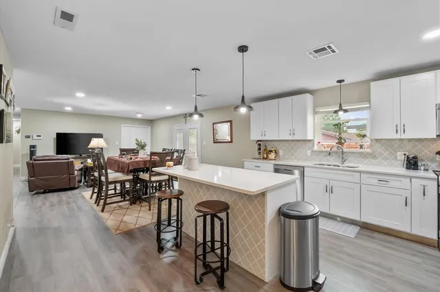 a kitchen with stainless steel appliances a dining table chairs stove and white cabinets
