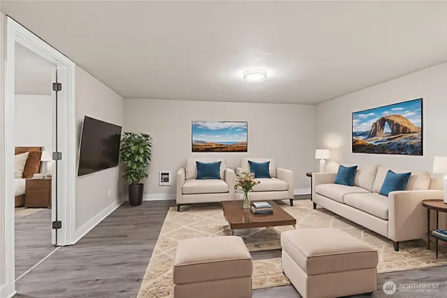 a living room with furniture two large window and a flat screen tv