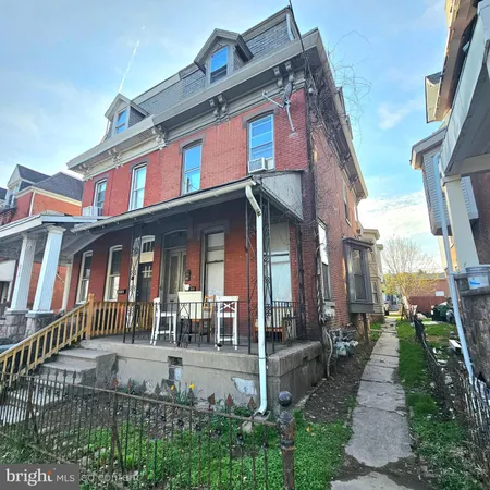 a view of a brick house with many windows and a yard