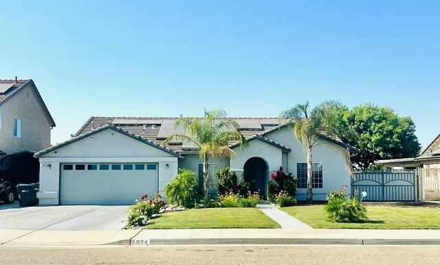 a front view of a house with a yard and potted plants