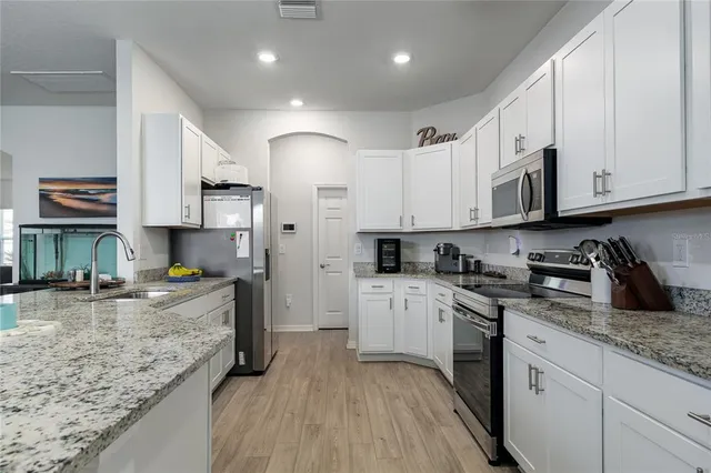 a kitchen with kitchen island granite countertop a sink a stove and cabinets