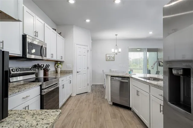 a kitchen with stainless steel appliances granite countertop a stove top oven a sink dishwasher a refrigerator and cabinets with wooden floor