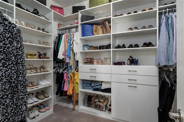 a view of walk in closet with clothes and shoes