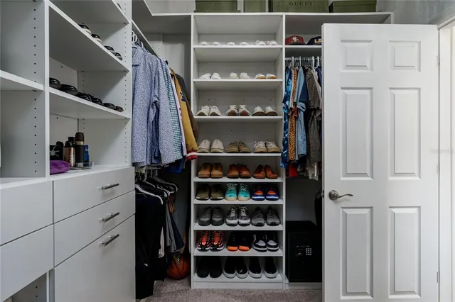 a view of walk in closet with clothes and shoes