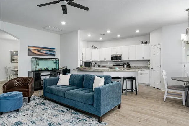 a living room with stainless steel appliances granite countertop couches a fireplace a flat screen tv and kitchen view