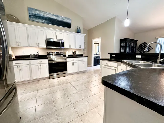 a kitchen with stainless steel appliances granite countertop a sink a stove top oven a counter space and cabinets