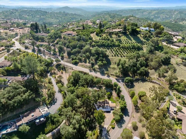 an aerial view of residential house with yard and mountain view in back