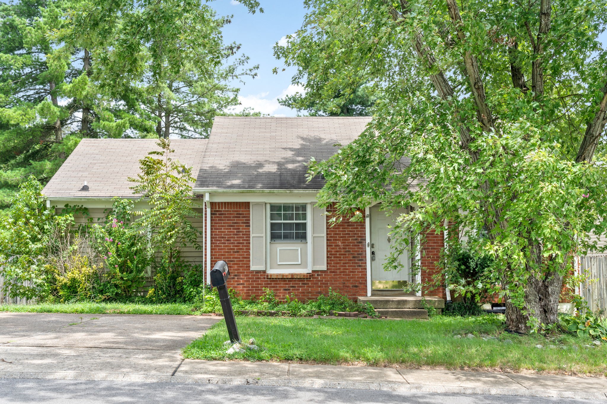 a view of a brick house with a yard and large trees