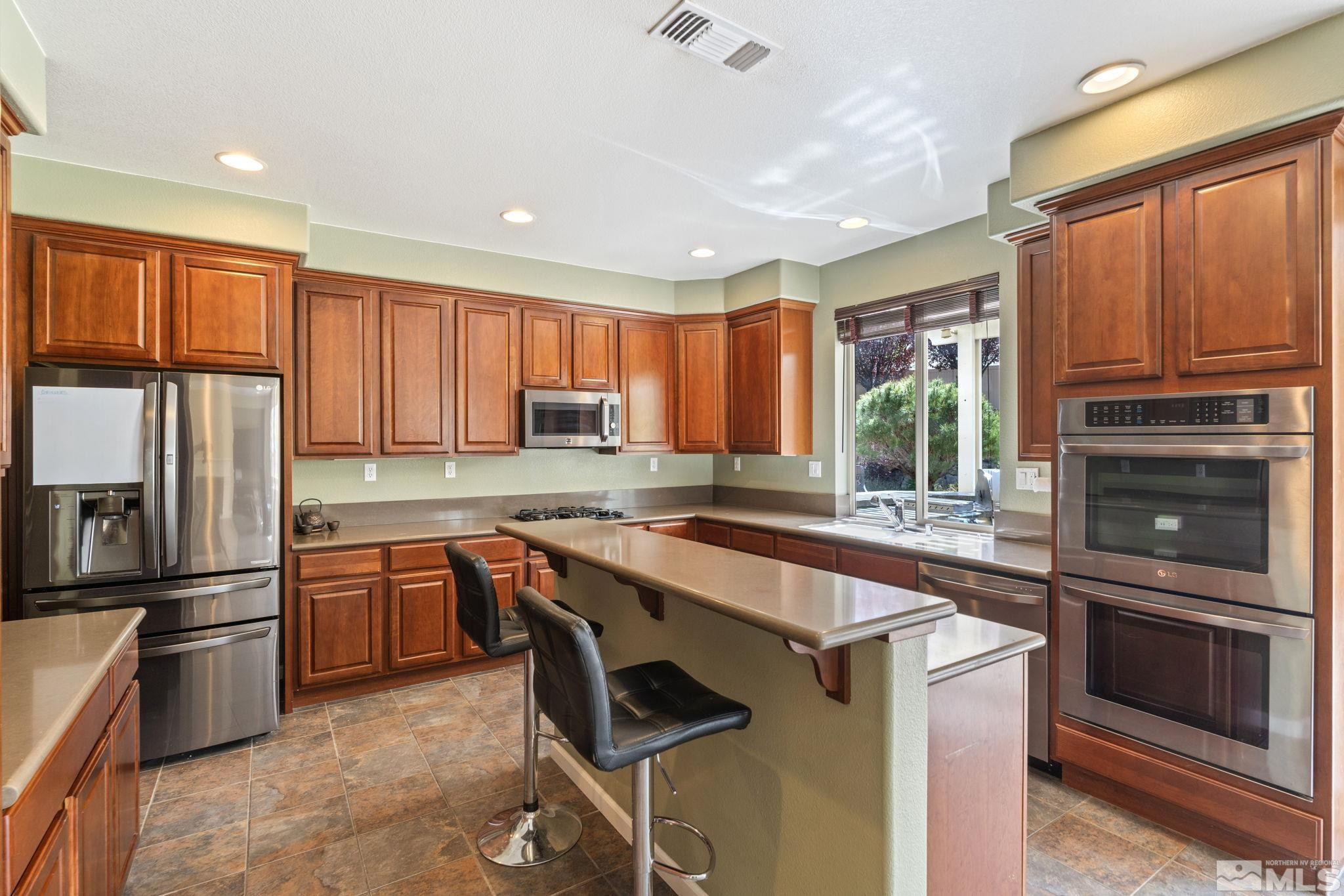 10890 Sand Hollow Court Reno, NV 89521 - Photo 13 of 40 a kitchen with stainless steel appliances granite countertop a stove top oven a sink and a refrigerator