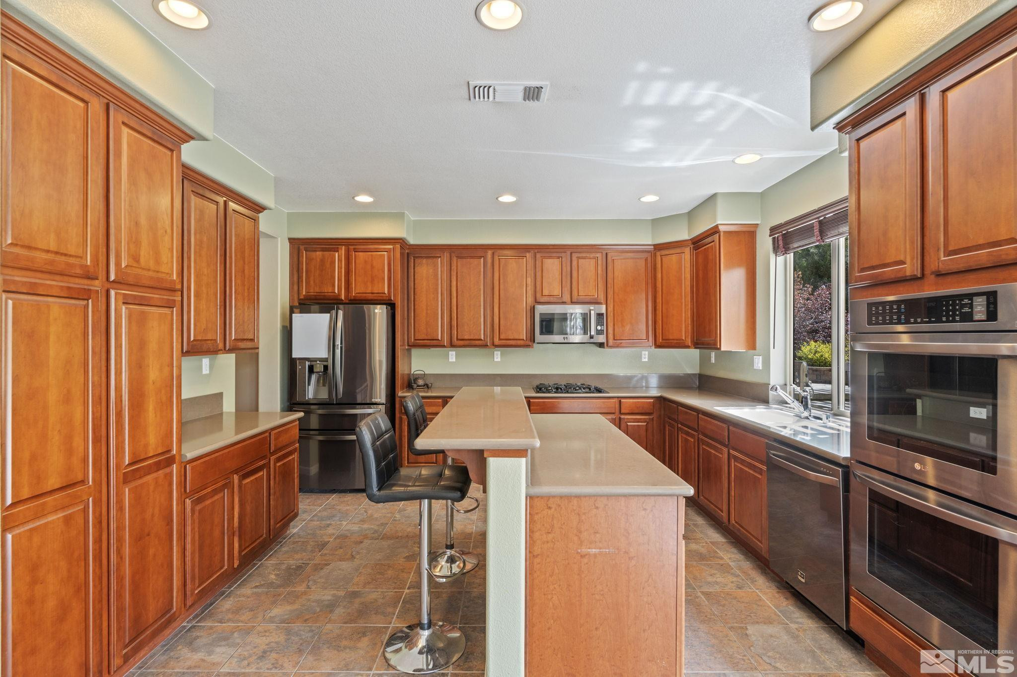 10890 Sand Hollow Court Reno, NV 89521 - Photo 14 of 40 a kitchen with stainless steel appliances kitchen island granite countertop a refrigerator a stove top oven a sink and dishwasher