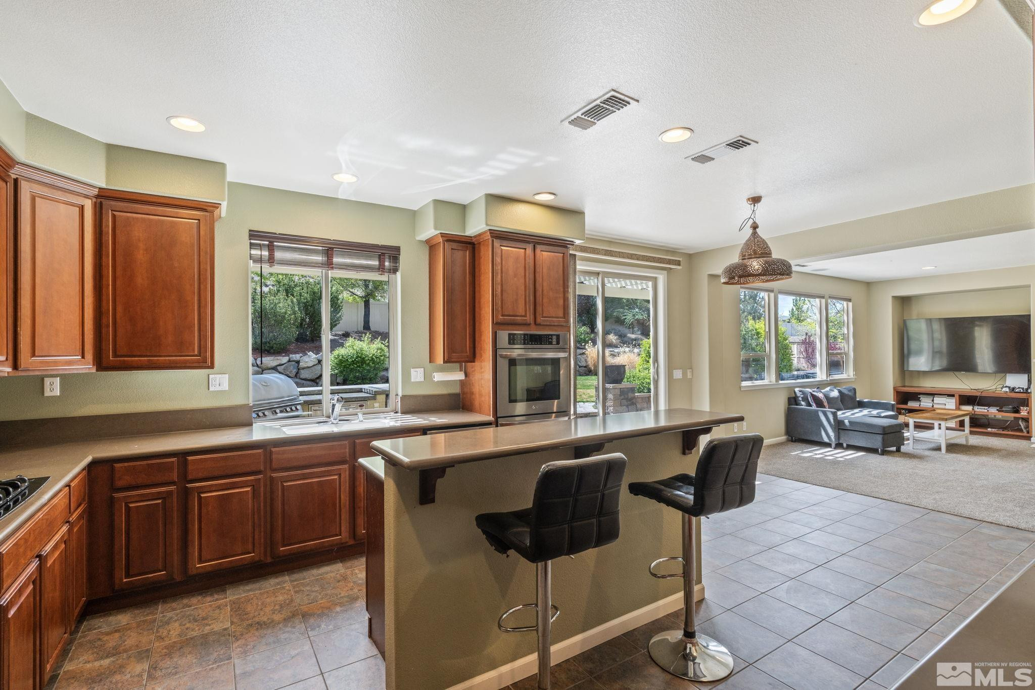 10890 Sand Hollow Court Reno, NV 89521 - Photo 15 of 40 a large kitchen with kitchen island granite countertop a stove a sink dishwasher a dining table and chairs with wooden floor