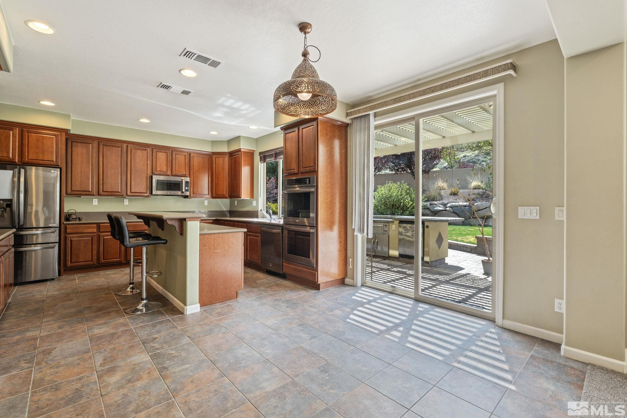 10890 Sand Hollow Court Reno, NV 89521 - Photo 10 of 40 a open kitchen with kitchen island granite countertop a refrigerator a stove top oven a sink with island and chairs