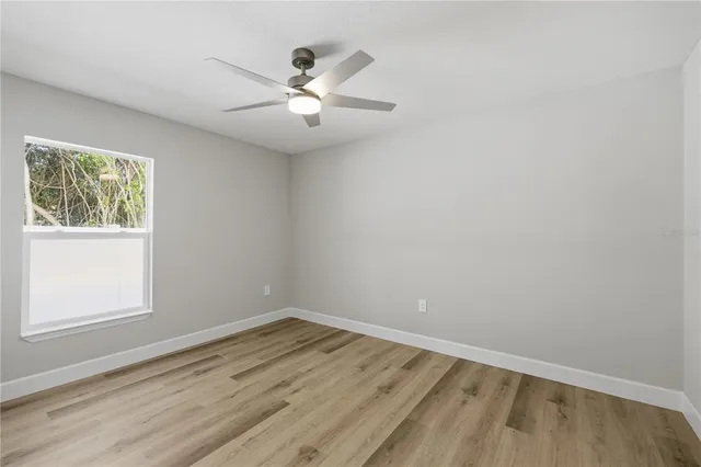 an empty room with a window and ceiling fan