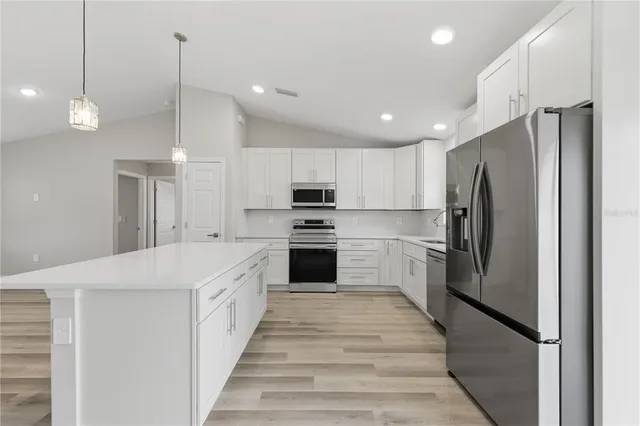 a large kitchen with a refrigerator a stove top oven and a center island