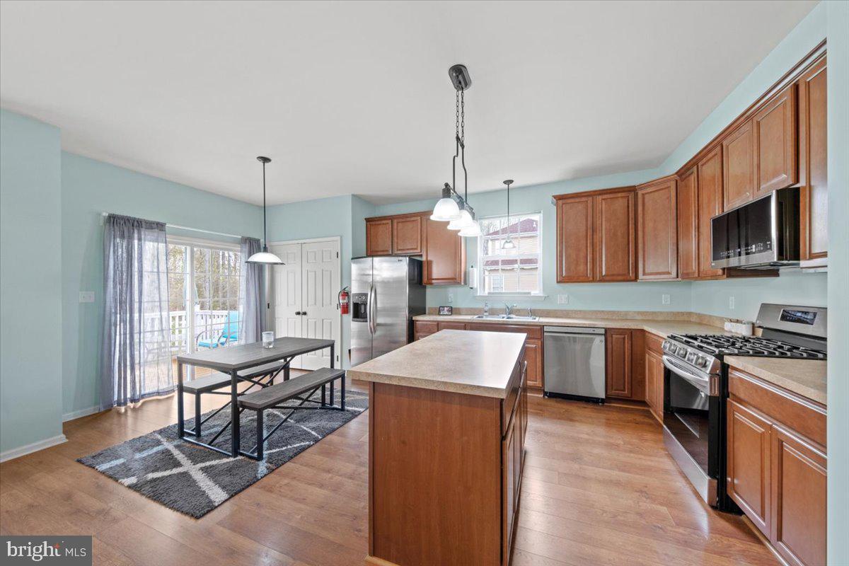 61 Homestead Drive Pemberton, NJ 08068 - Photo 5 of 40 a kitchen with stainless steel appliances granite countertop a stove top oven a sink dishwasher a dining table and chairs with wooden floor