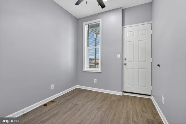 a view of an empty room with wooden floor and a window