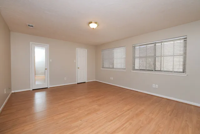 a view of an empty room with wooden floor and a window