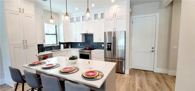 a kitchen with stainless steel appliances granite countertop a refrigerator a stove a sink and a dining table with chairs