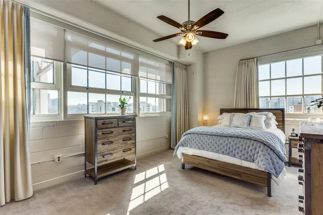 a spacious bedroom with a bed a dresser and a large window
