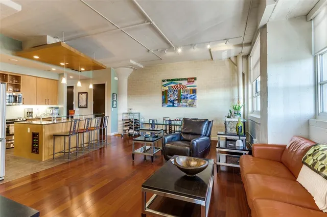 a living room with furniture kitchen view and a wooden floor