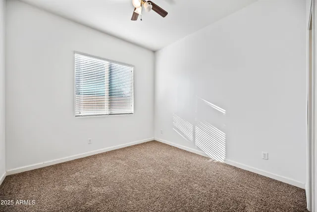 an empty room with a window and ceiling fan