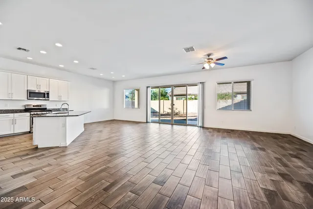 a view of an empty room with window and wooden floor
