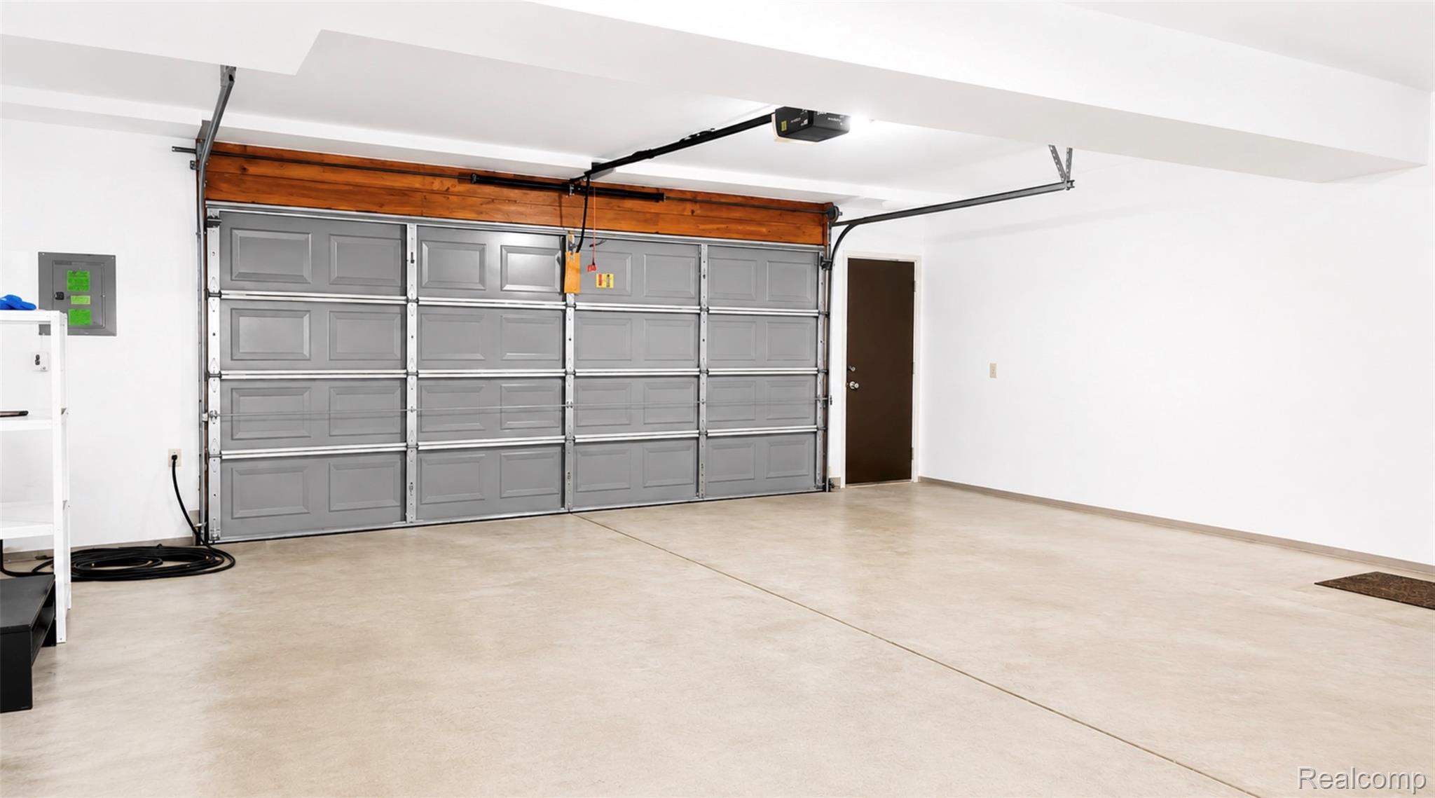 2232 London Bridge Drive, Unit 42 Rochester, MI 48307 - Photo 19 of 20 Spacious garage with a light-colored concrete floor, bright white walls, and an automatic gray sectional garage door