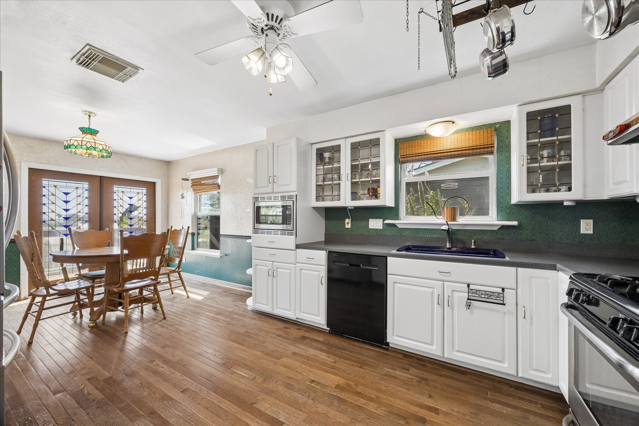 1009 3rd Street Seabrook, TX 77586 - Photo 7 of 20 a kitchen with stainless steel appliances granite countertop a stove top oven a sink dishwasher a dining table and chairs with wooden floor