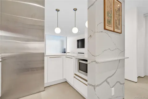 a white kitchen with a sink and dishwasher a refrigerator with white cabinets