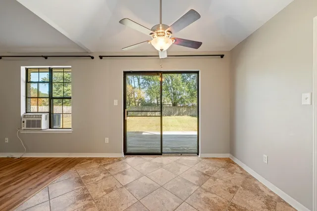 an empty room with window and ceiling fan