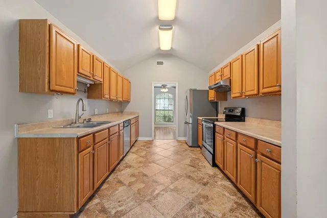 a kitchen with stainless steel appliances a sink stove top oven and cabinets